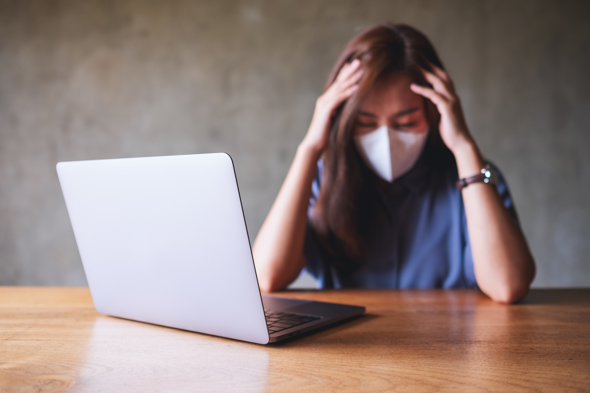 Businesswoman with protective face mask get stressed while working on laptop computer in office