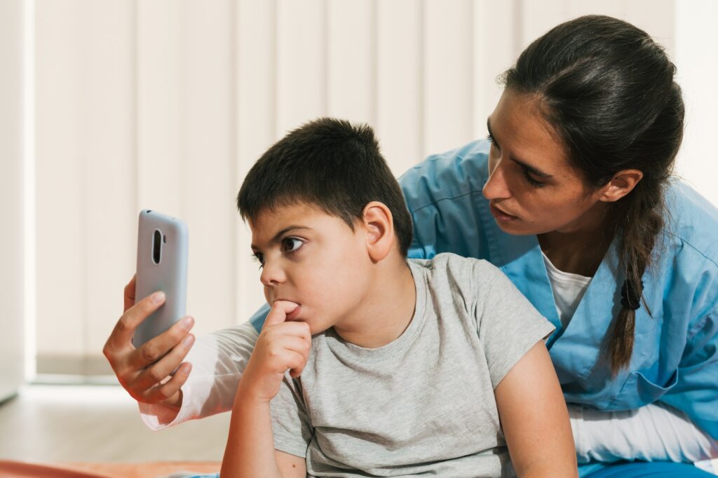 Physiotherapist assisting child using smartphone for visual tracking and attention therapy