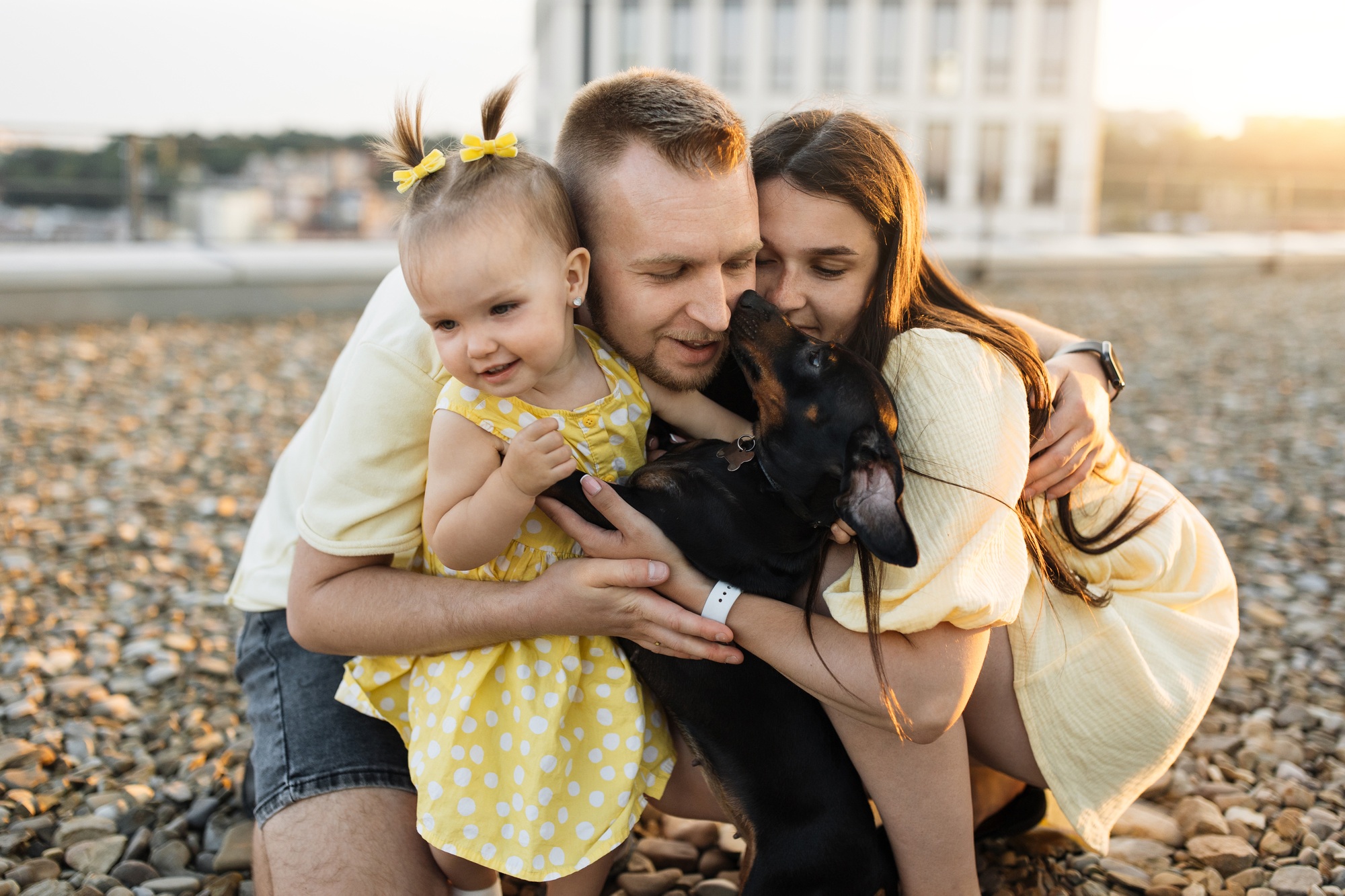Positive parents embracing daughter and dachshund on rooftop