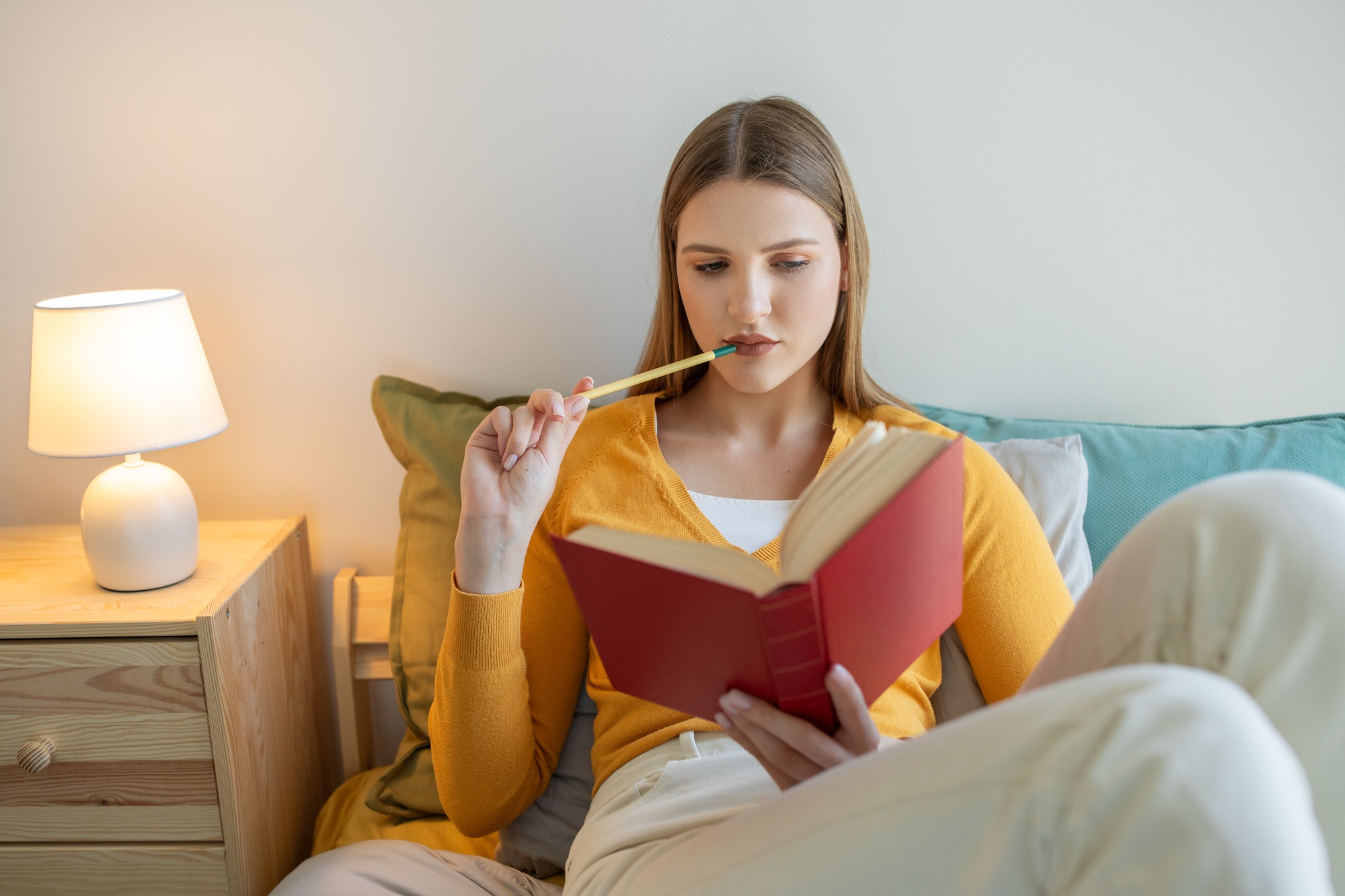 Teen Girl Sitting on Bed Reading Book