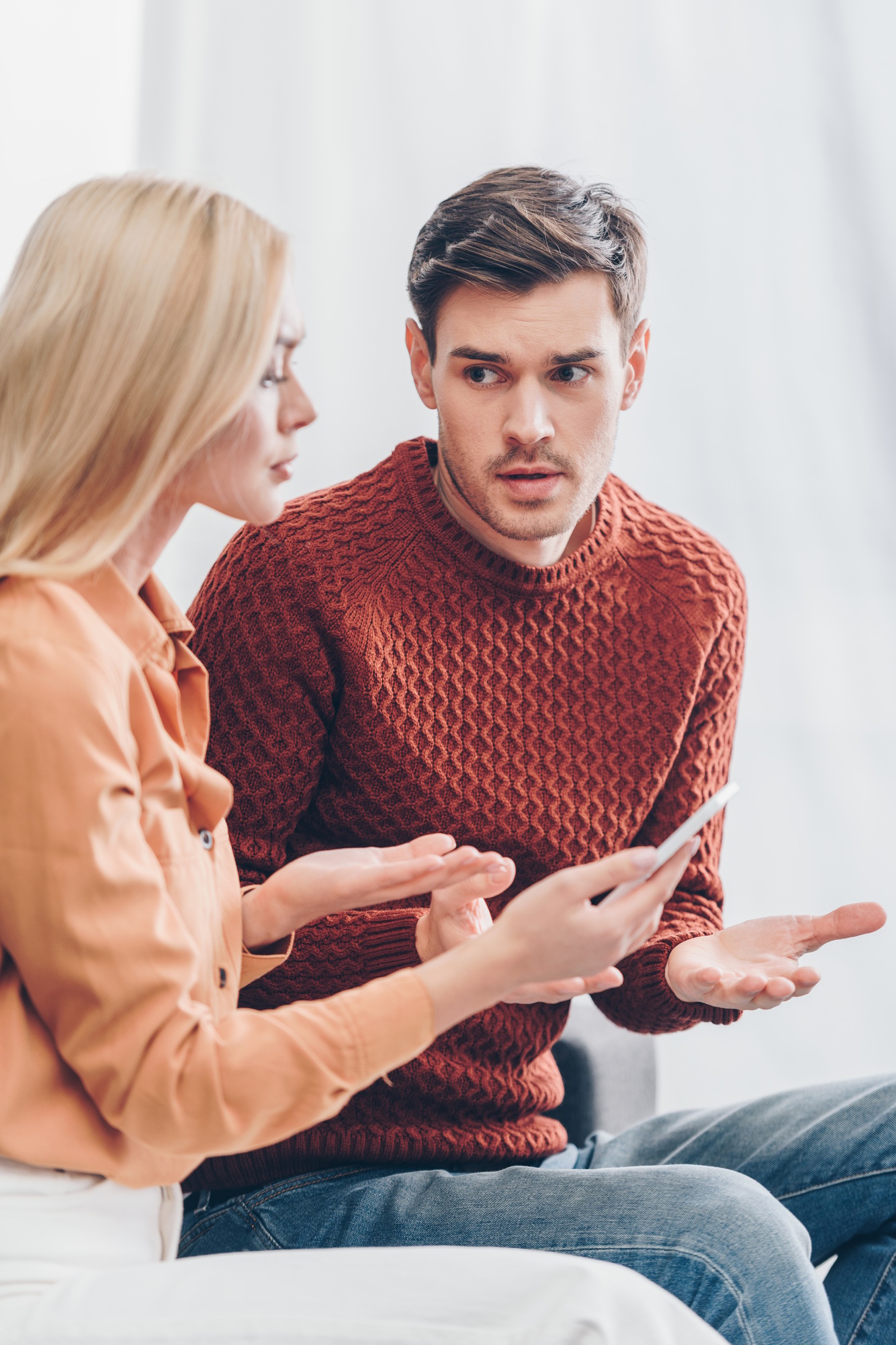 young couple quarreling about smartphone at home, jealousy concept